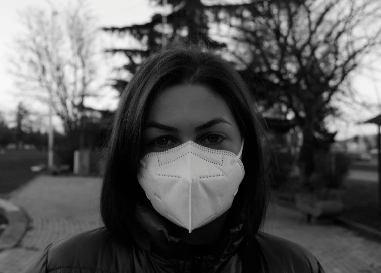 a black and white photo of a woman wearing a face mask, a black and white photo, pexels, purism, front portrait of a girl, protection, low quality, photo of džesika devic