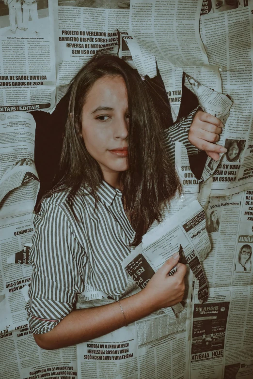 a woman standing in front of a wall covered in newspapers, by Alejandro Obregón, pexels contest winner, isabela moner, holding a stuff, promo image, instagram picture
