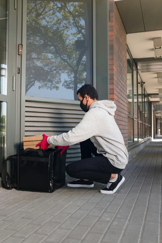 a man sitting on the ground with a piece of luggage, exiting store, delivering parsel box, at college, profile image