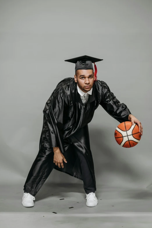 a man in a graduation gown holding a basketball, dribble, trending photo, brom gerald, diverse ages, soccer player