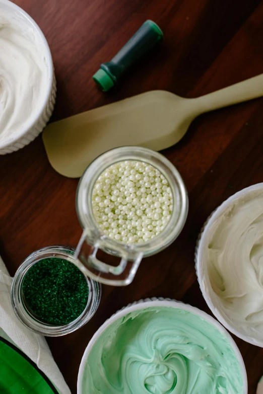 a wooden table topped with white frosting and green sprinkles, trending on unsplash, process art, green color scheme, white pearlescent, corn, close-up product photo