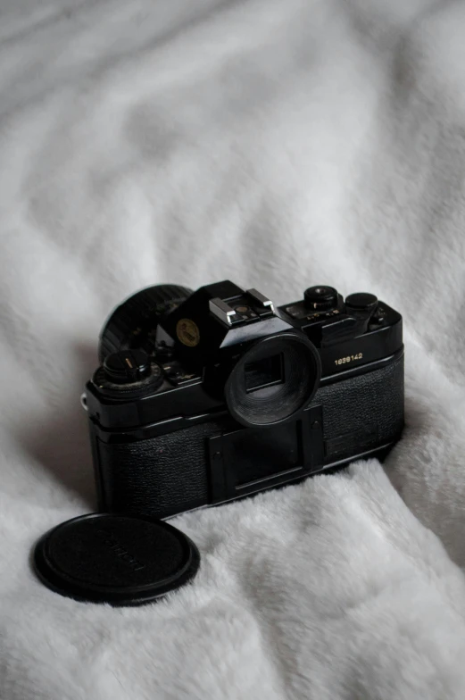 a black camera sitting on top of a white blanket, a picture, by Adam Rex, unsplash, minimalism, film artifacts, olympus, lofi, hyperdetailed photograph