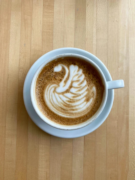 a cup of coffee sitting on top of a wooden table, by Carey Morris, floating spiral sand, thumbnail, vanilla, intricate! organic