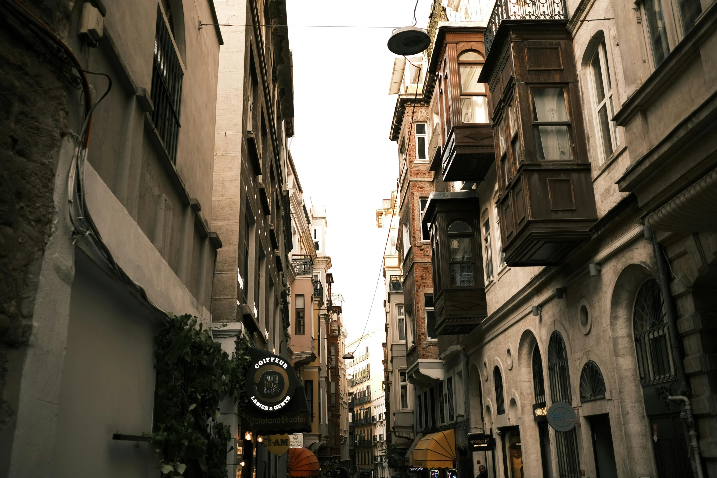 a person walking down a narrow street with an umbrella, by Ismail Acar, pexels contest winner, renaissance, fallout style istanbul, house's and shops and buildings, beige, late afternoon