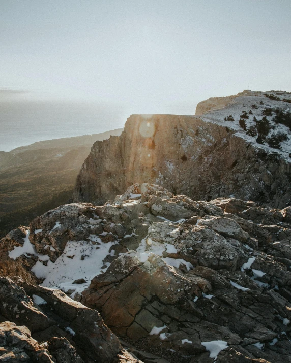 a person standing on top of a snow covered mountain, in socotra island, golden hour photography, rocky cliff, set photo