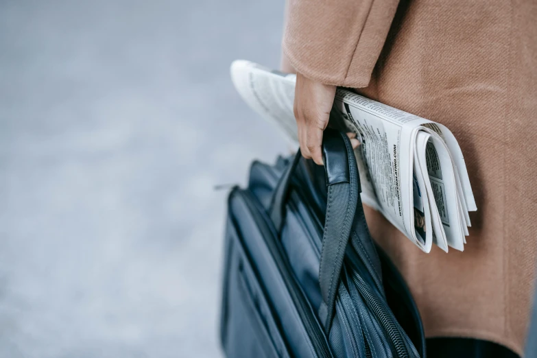 a close up of a person holding a bag, by Carey Morris, trending on unsplash, newspaper, square backpack, holding books, 15081959 21121991 01012000 4k