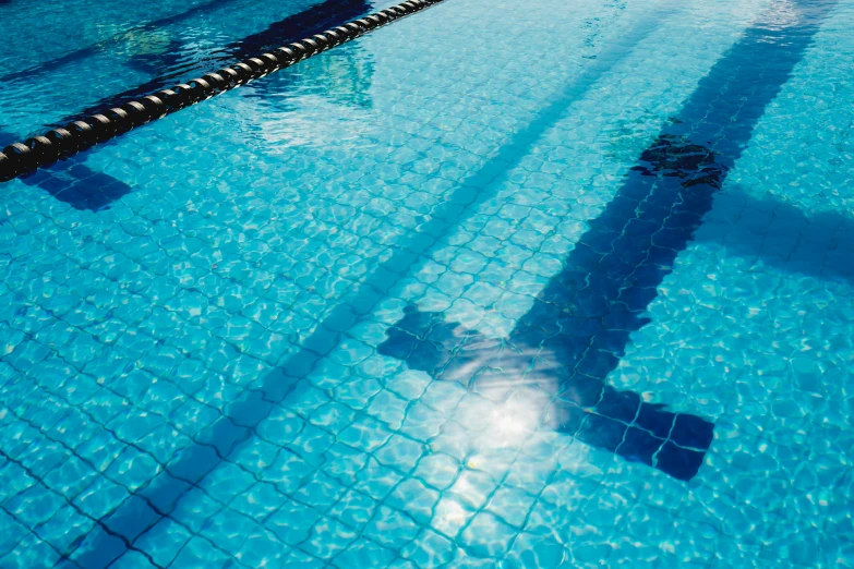 a swimming pool filled with lots of blue water, by Helen Stevenson, shutterstock, sunlight shining through, sports photo, taken with kodak portra, caulfield