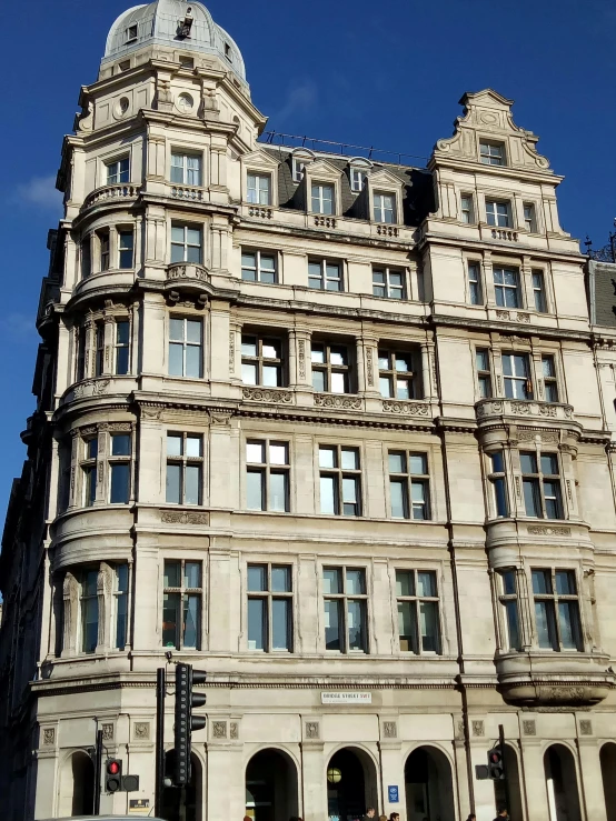 a tall building sitting on the corner of a street, inspired by Christopher Wren, art nouveau, limestone, very pretty, vivienne westwood, exterior photo