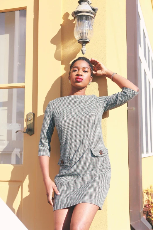 a woman standing in front of a yellow door, instagram, in gunmetal grey, tailored clothing, sixties pinup, maria borges