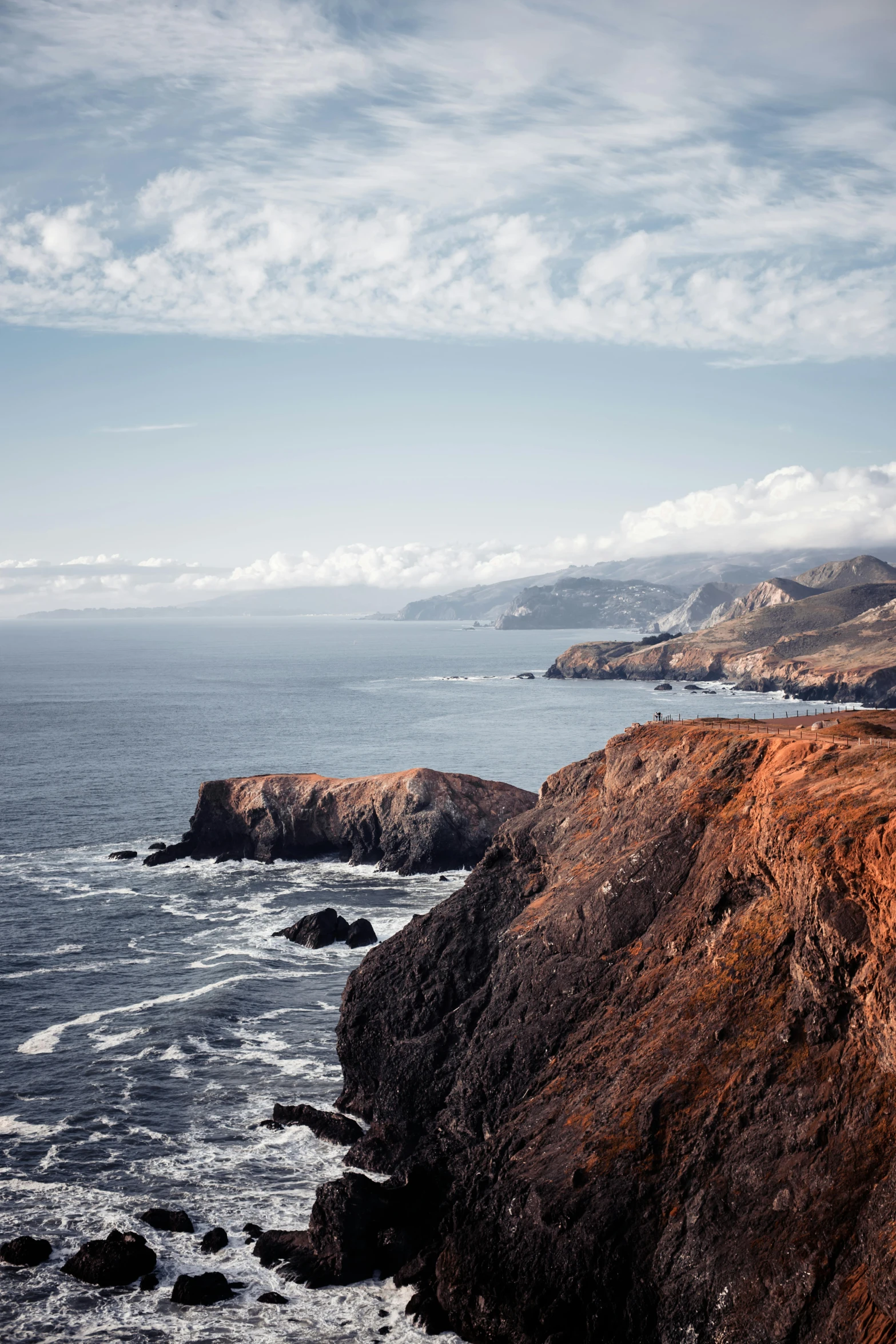 a lighthouse sitting on top of a cliff next to the ocean, craggy mountains, muted browns, bay area, coastal cliffs