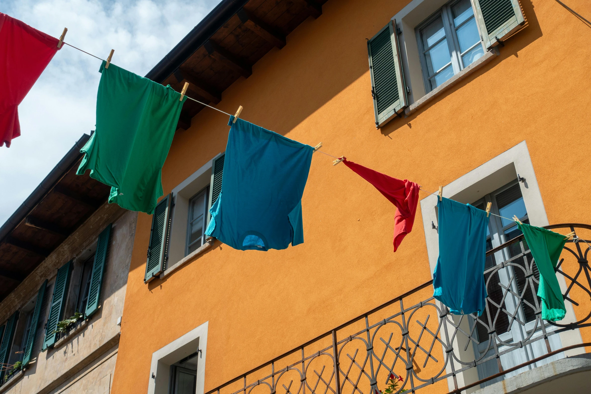 clothes hanging on a clothes line in front of a building, inspired by Michelangelo Buonarotti, pexels contest winner, arte povera, chartreuse and orange and cyan, french village exterior, red pennants, youtube thumbnail