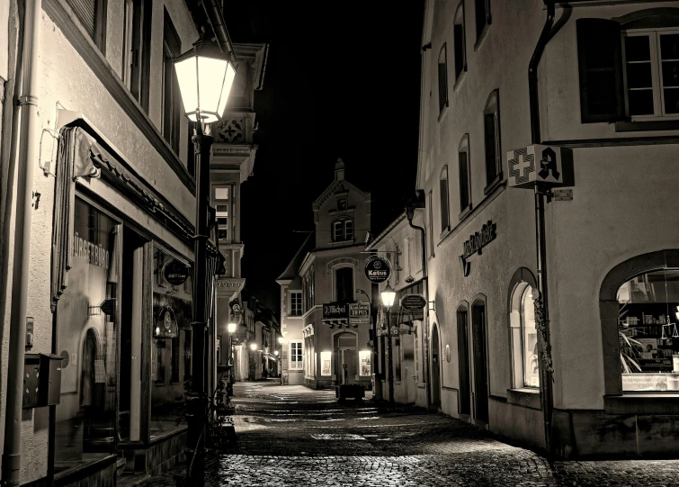 a black and white photo of a street at night, a black and white photo, pexels contest winner, detmold, square, historical, cozy