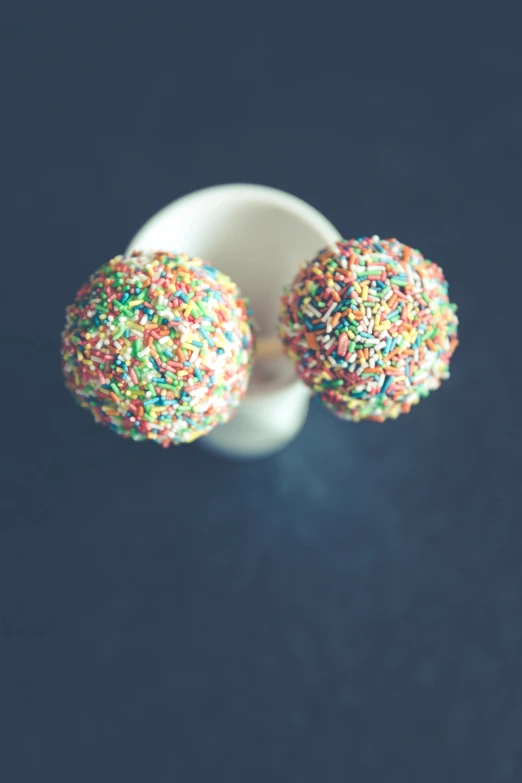 a couple of sprinkles sitting on top of a white cup, pexels, pointillism, small studded earings, colorful]”, grainy photo, in 2 0 1 2