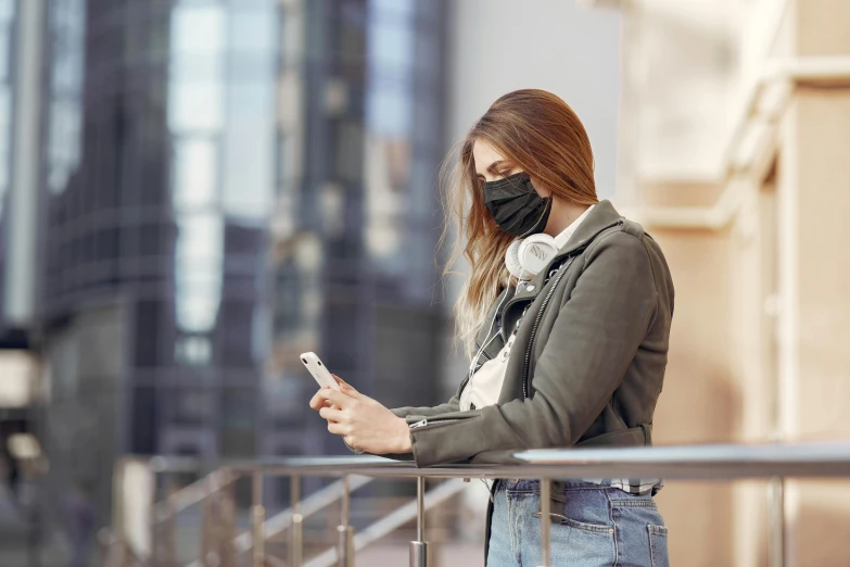 a woman wearing a face mask looking at her phone, trending on pexels, urban in background, avatar image, casually dressed, worksafe. instagram photo