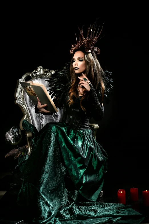 a woman dressed as a witch reading a book, an album cover, inspired by Samuel Hieronymus Grimm, pexels contest winner, gothic art, sitting in a gilded throne, ornate dark green clothing, wearing crown of bright feathers, fashion photograhy