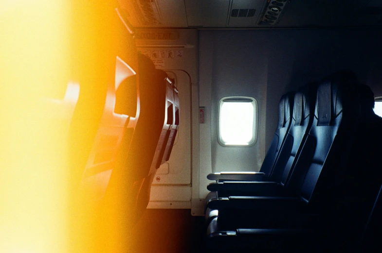 a row of empty seats in an airplane, pexels, light and space, shades of aerochrome gold, the sun reflecting on a window, black and yellow and red scheme, max dennison