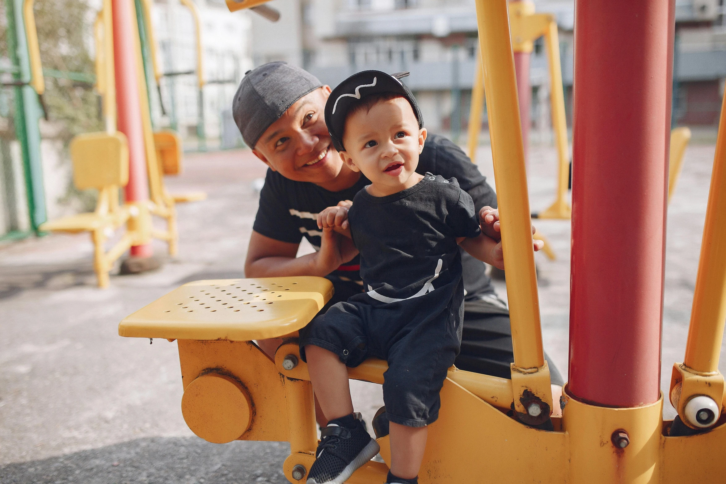 a man sitting next to a little boy on a playground, by Julia Pishtar, pexels contest winner, square, 15081959 21121991 01012000 4k, ruan jia and brom, black