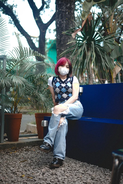 a woman sitting on a blue bench wearing a face mask, an album cover, trending on pexels, outfit : jeans and white vest, cosplay photo, set on singaporean aesthetic, at college