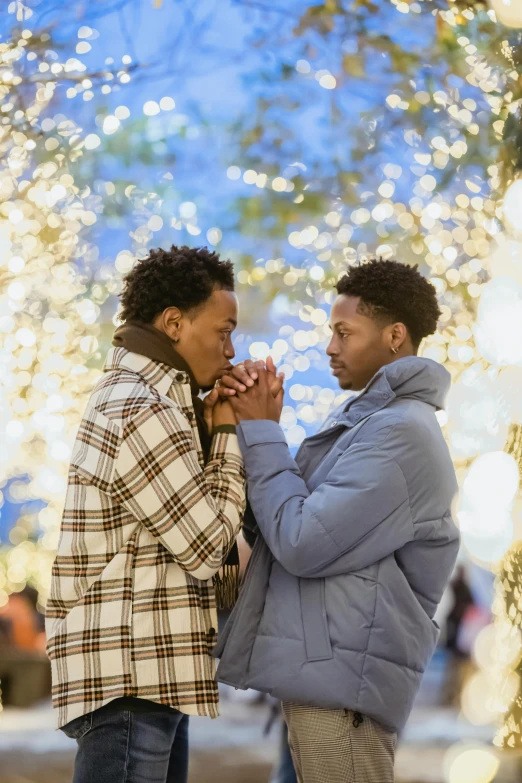 a man and woman standing next to each other in front of christmas lights, by Dorothy Bradford, pexels, romanticism, two young men, : kendrick lamar, in a mall, comforting