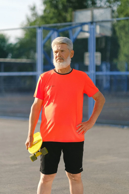 a man standing on a tennis court holding a yellow frisbee, inspired by Jan Müller, wearing an orange t shirt, old man, paul barson, profile image