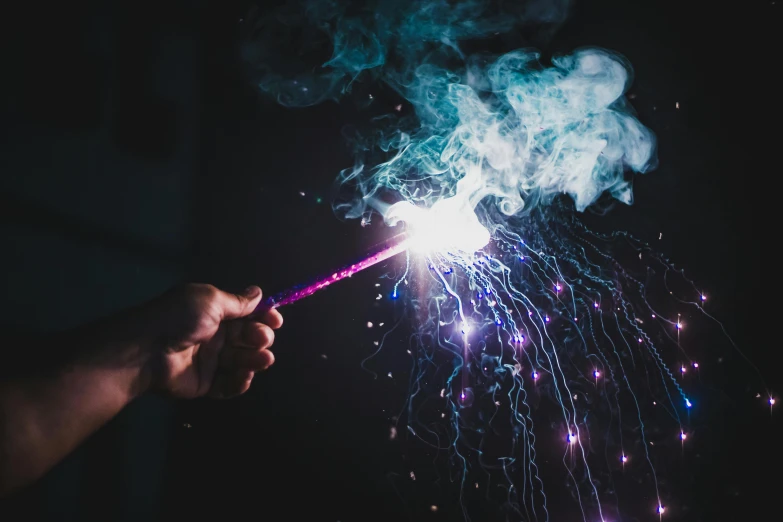 a person holding a sparkler in their hand, pexels contest winner, purple and blue, smoking soldering iron, long trunk holding a wand, shockwaves are coming out