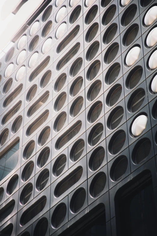 a very tall building with a lot of holes on it, an album cover, unsplash, brutalism, round windows, panel of black, metallic shutter, moma