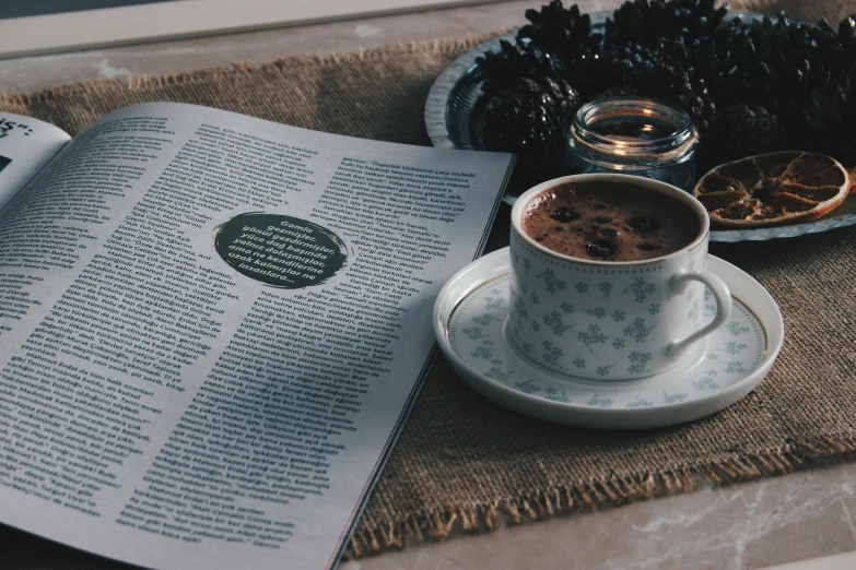 a book sitting on top of a table next to a cup of coffee, a picture, full page periodical image, chocolate, thumbnail, cozy wallpaper