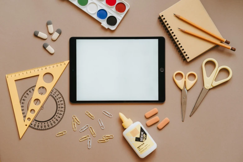 a tablet computer sitting on top of a table, by Julia Pishtar, trending on pexels, computer art, knolling, teacher, brown and cream color scheme, art supplies