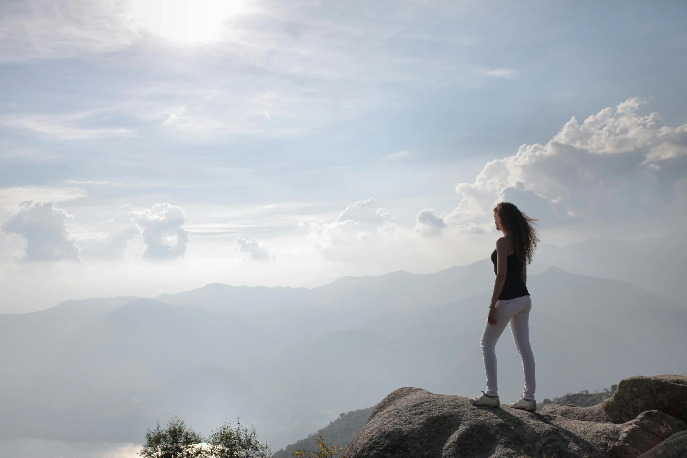 a woman standing on top of a large rock, pexels contest winner, uttarakhand, profile image, girl clouds, sunny day time