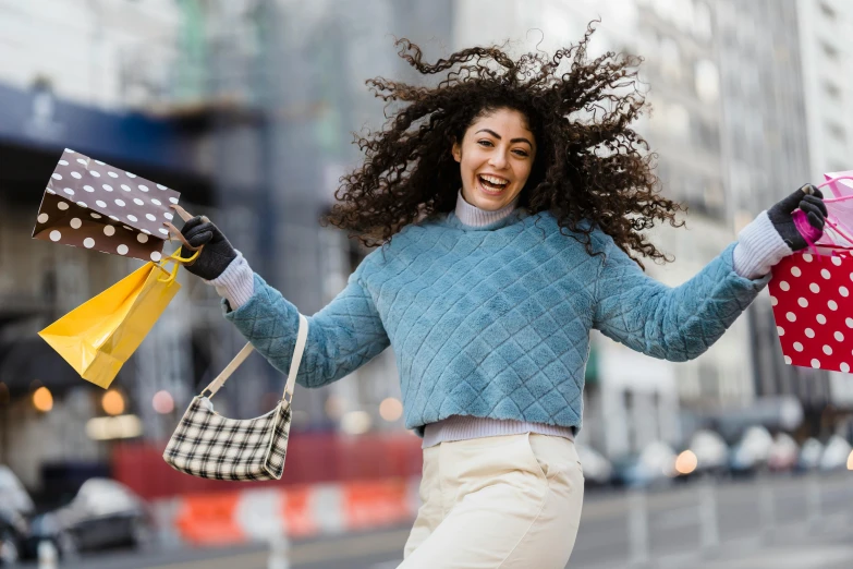 a woman walking down the street holding shopping bags, pexels contest winner, happening, wavy hair spread out, cheering, lorde, wearing a sweater