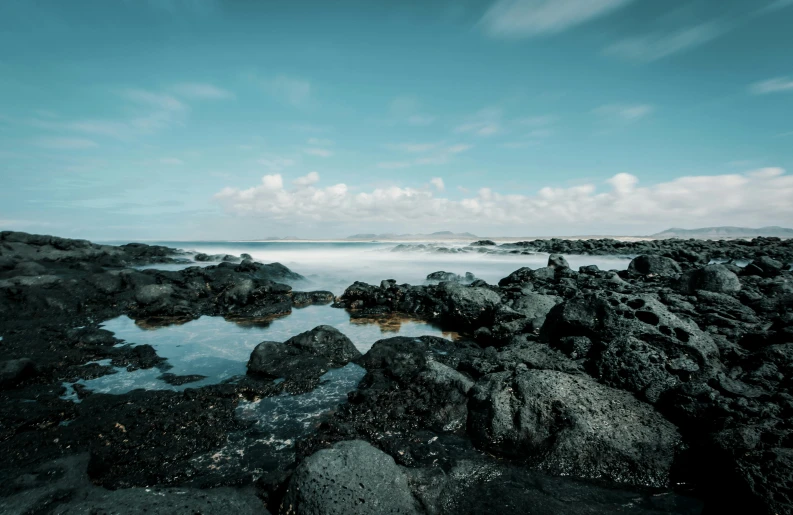 a large body of water sitting on top of a rocky beach, pexels contest winner, reykjavik, 4k image”, slow shutter speed, cloudless-crear-sky