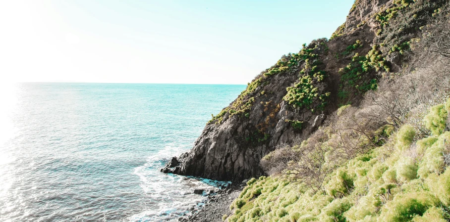 a man standing on top of a cliff next to the ocean, vibrant greenery, marbella, instagram photo, thumbnail