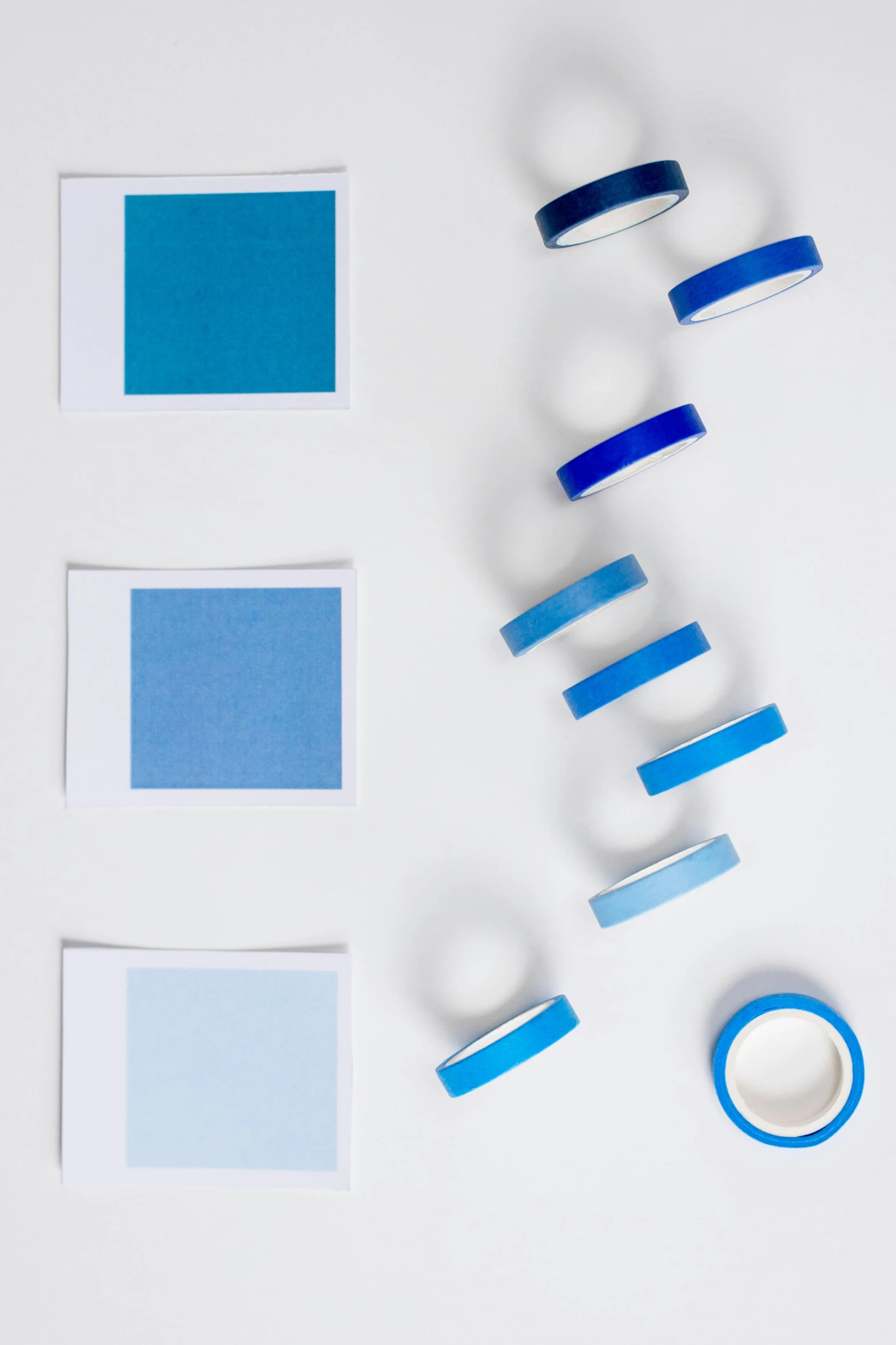 a number of different colors of tape on a white surface, inspired by Ellsworth Kelly, trending on unsplash, color field, blue glow, desaturated blue, square shapes, productphoto