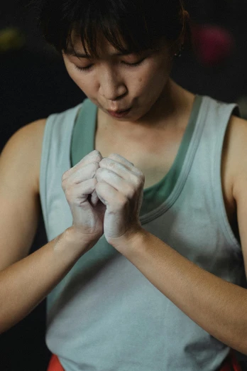 a close up of a person holding something in their hands, a portrait, inspired by Wen Jia, pexels contest winner, bandage taped fists, sweat, asian woman, getting ready to fight