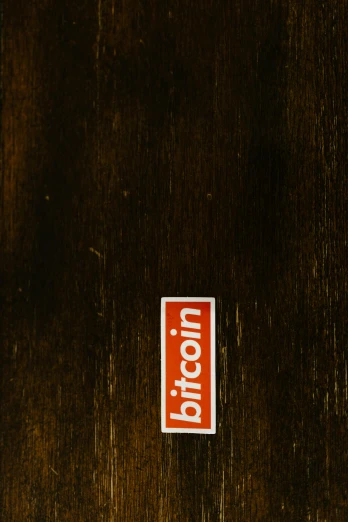 a red box sitting on top of a wooden floor, by Benjamin Block, unsplash, graffiti, bitcoin, square sticker, brown, front label