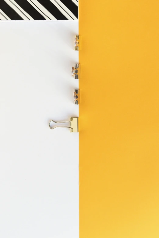 a notepad sitting on top of a yellow and white desk, by Jean-Yves Couliou, trending on unsplash, postminimalism, lock, split in half, gold and white, 3/4 view from below