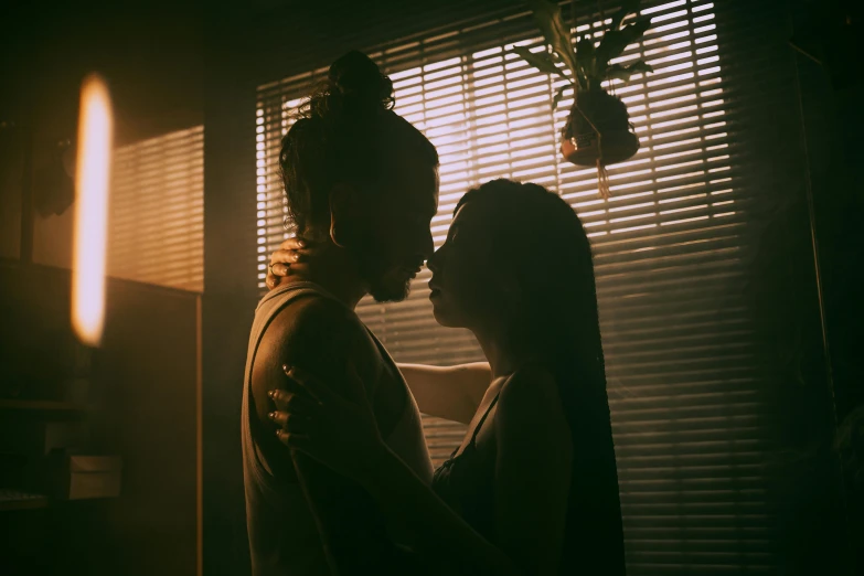 a man and a woman standing in front of a window, a picture, inspired by Elsa Bleda, pexels contest winner, reylo kissing, dimly lit room, still from a music video, jordan grimmer and natasha tan