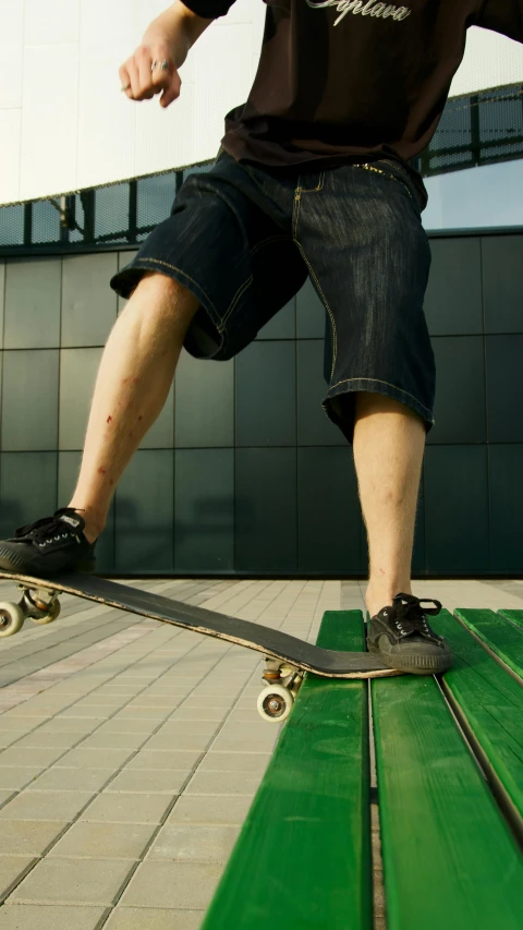 a man riding a skateboard on top of a green bench, by Ben Zoeller, shutterstock, shows a leg, low quality photo, thumbnail