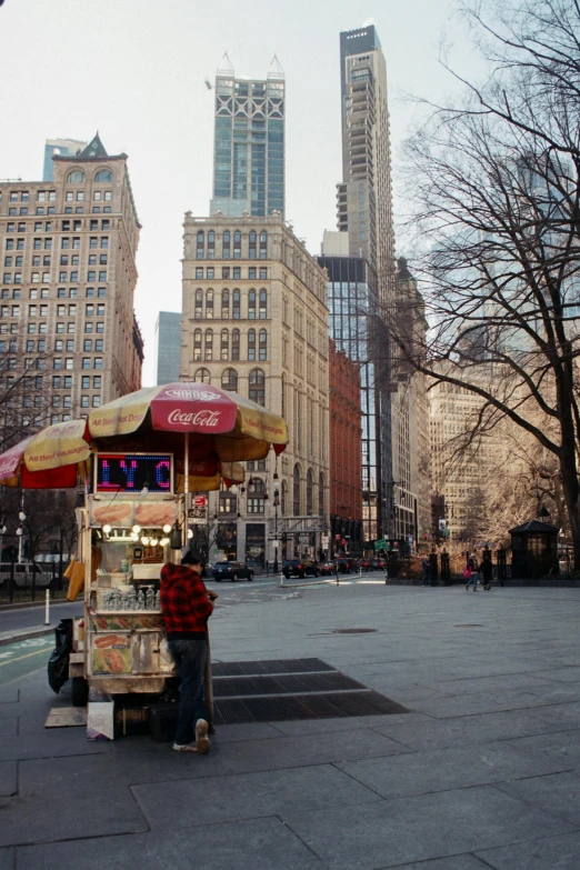 a food cart on a city street with tall buildings in the background, a picture, inspired by Ruth Orkin, trending on unsplash, madison square garden, 1996), empty streetscapes, chilly