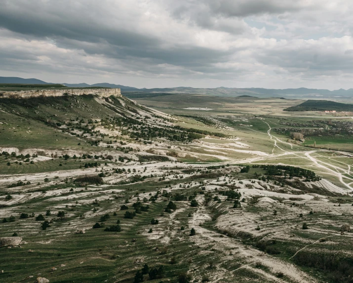 a man flying a kite on top of a lush green hillside, unsplash contest winner, les nabis, white travertine terraces, rocky ground with a dirt path, west slav features, stormy landscape