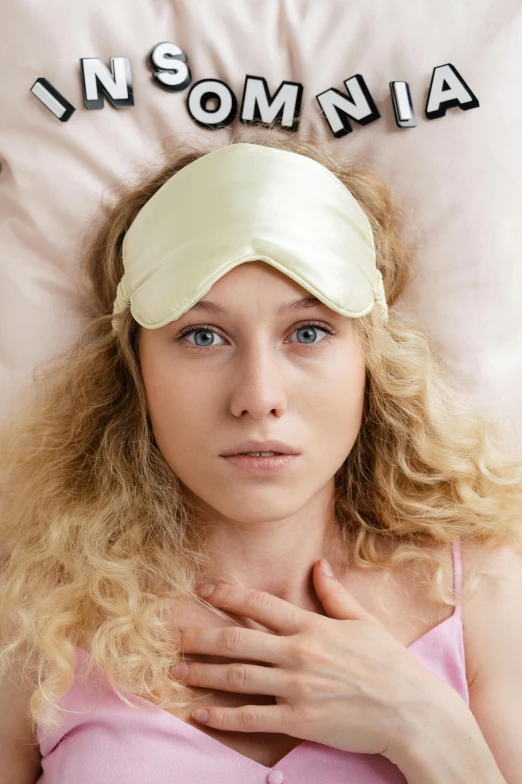 a woman laying on top of a bed next to a pillow, by Julia Pishtar, shutterstock, renaissance, pink headband, blonde cream, sad face, pearlescent skin