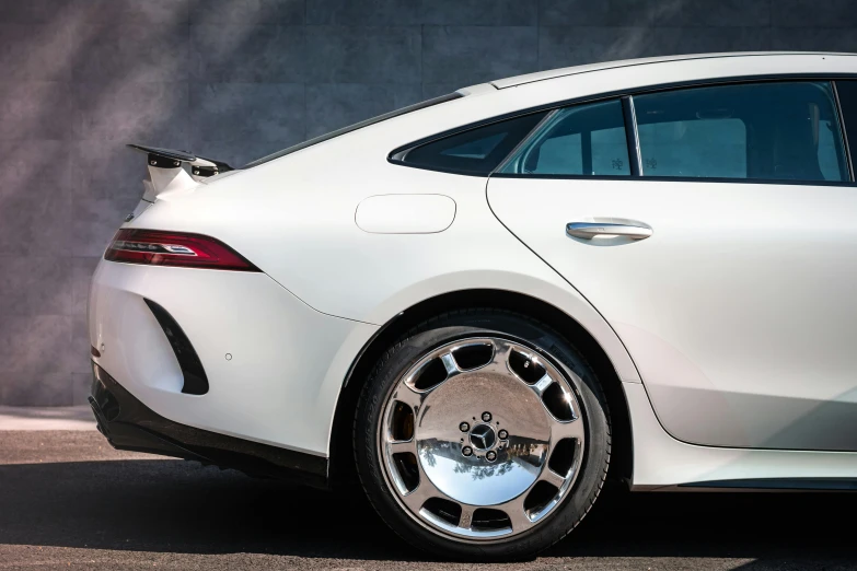 a white car parked in front of a wall, inspired by Harry Haenigsen, trending on pexels, detailed alloy wheels, rear shot, made out of shiny white metal, mercedes