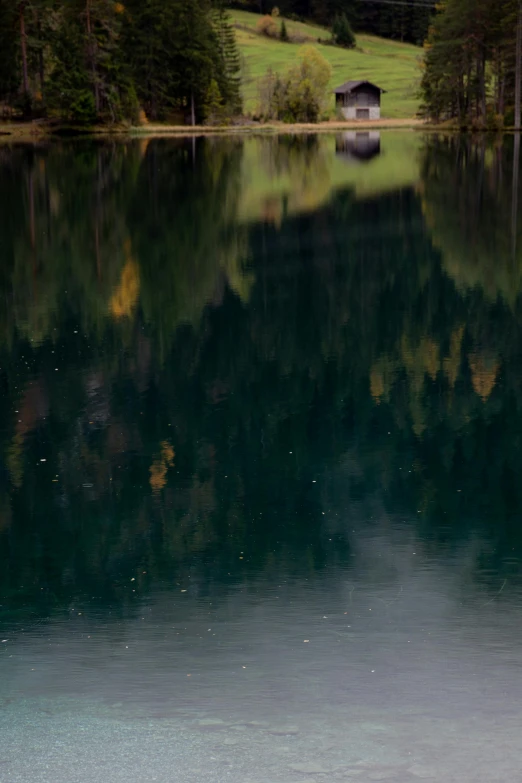 a boat sitting on top of a lake next to a forest, a picture, by Jan Rustem, tonalism, reflect photograph, unfocused, cinematic shot ar 9:16 -n 6 -g, small lake