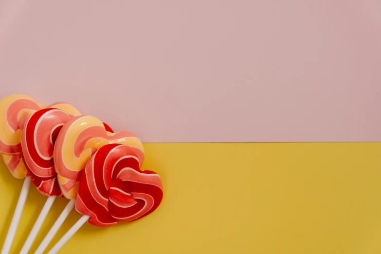 three lollipops on a yellow and pink background, trending on pexels, background image, red yellow, made out of sweets, minimalist photo