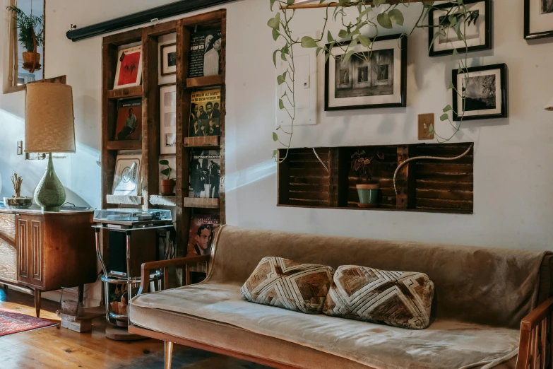 a couch sitting in a living room next to a window, maximalism, simple wood shelves, portrait featured on unsplash, vintage photo, small hipster coffee shop