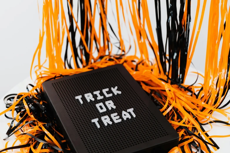 a black speaker with a trick or treat written on it, by Emma Andijewska, trending on pexels, ascii art, cereal box, revealing wires and electronics, close - up portrait shot, black and orange colour palette