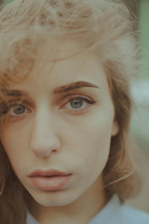 a close up of a person with long hair, inspired by Elsa Bleda, trending on pexels, photorealism, pale skin curly blond hair, attractive girl, grainy vintage, wide eyed