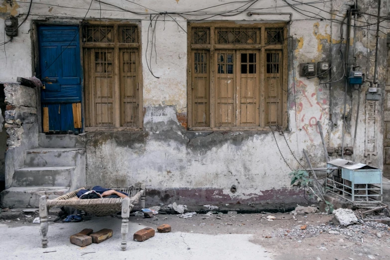 a person laying on a bench in front of a building, inspired by Steve McCurry, pexels contest winner, arte povera, inside a cluttered bedroom, on an indian street, exposed wires, 2 0 0 0's photo