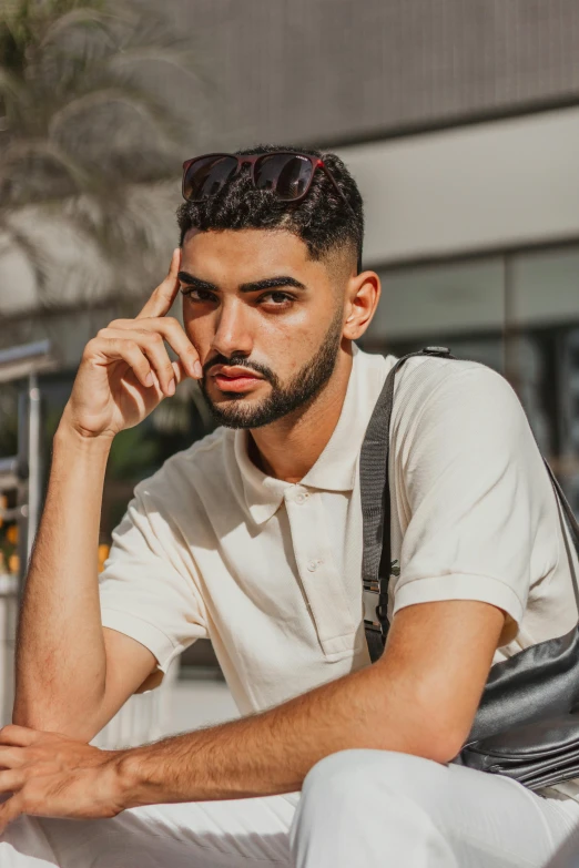 a man sitting on a bench talking on a cell phone, an album cover, trending on pexels, renaissance, middle eastern skin, wearing polo shirt, unibrow, non binary model