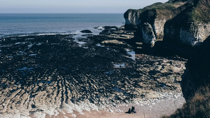 a person standing on a rocky beach next to the ocean, english heritage, gigapixel photo, huge chasm, 4k image”